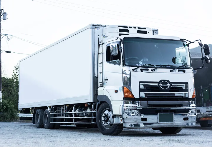 側面が白く塗装された業務用のトラックが駐車されている様子。